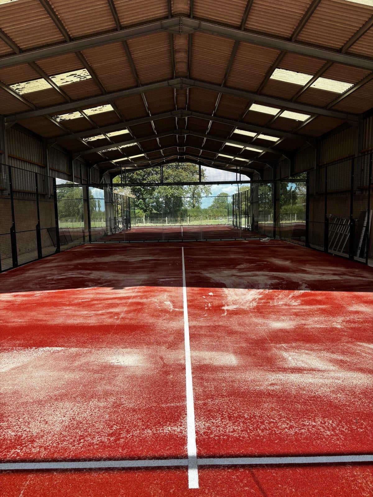 Terracotta padel court inside a barn 