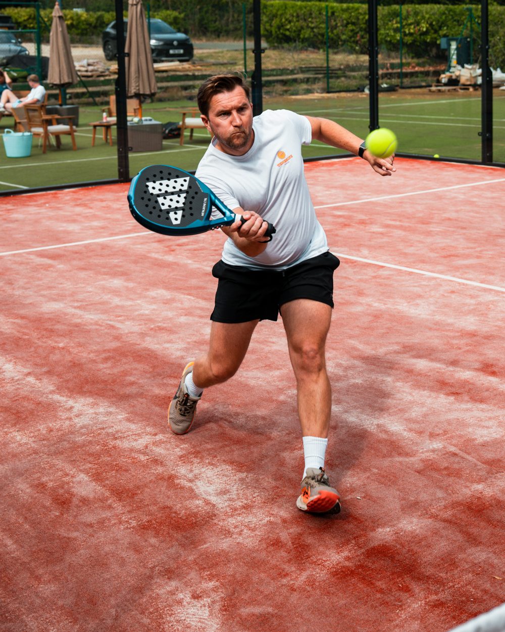 Padel player hitting a forehand during a social Mexicano