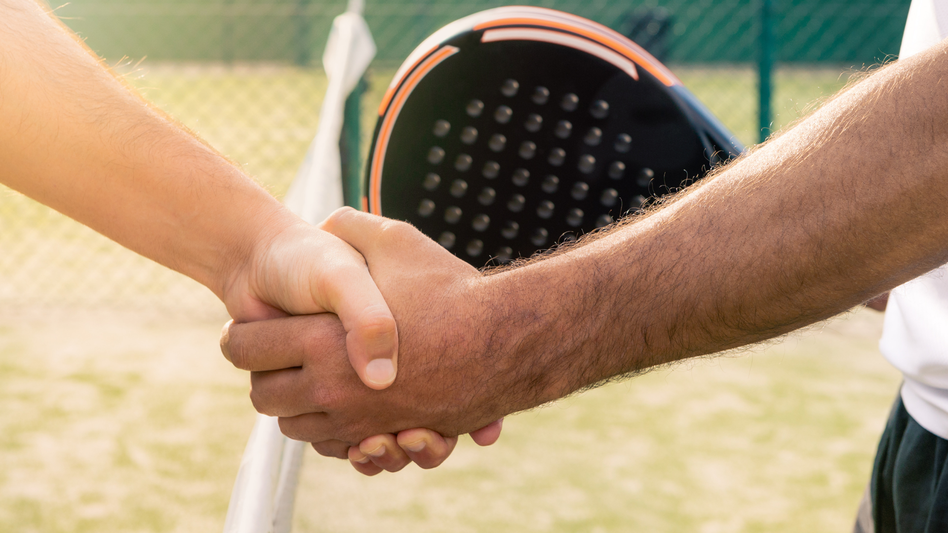 Two people shaking hands over a padel tennis net