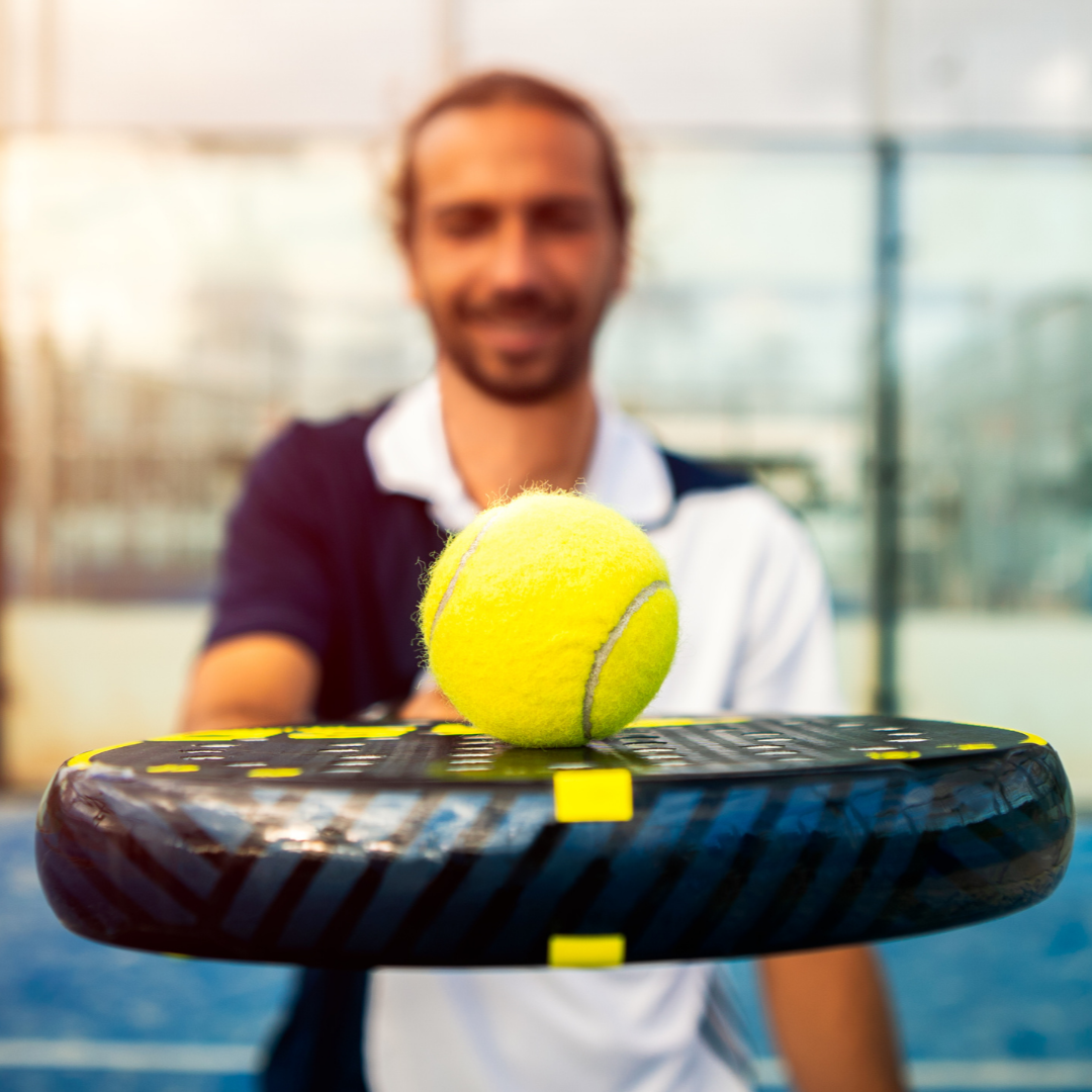 Man holding a tennis ball on a padel racquet in an indoor sports facility