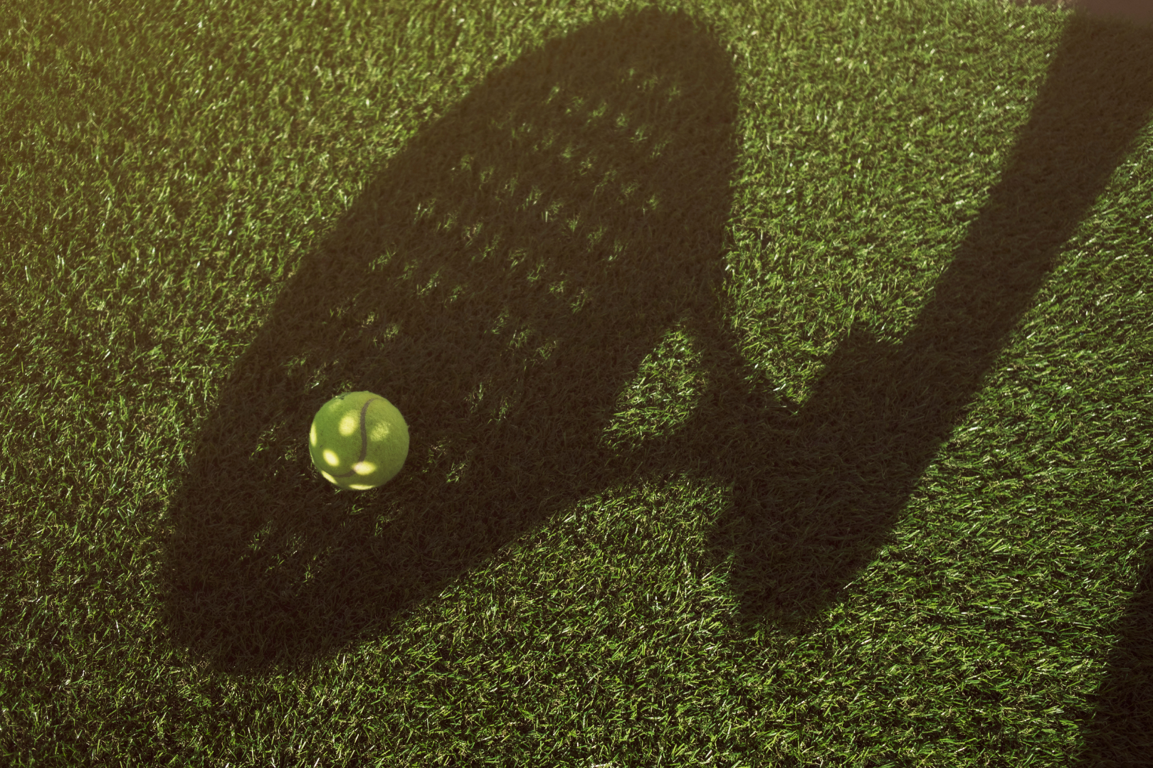 Close up of the shadow of a padel racquet and ball on artificial green turf
