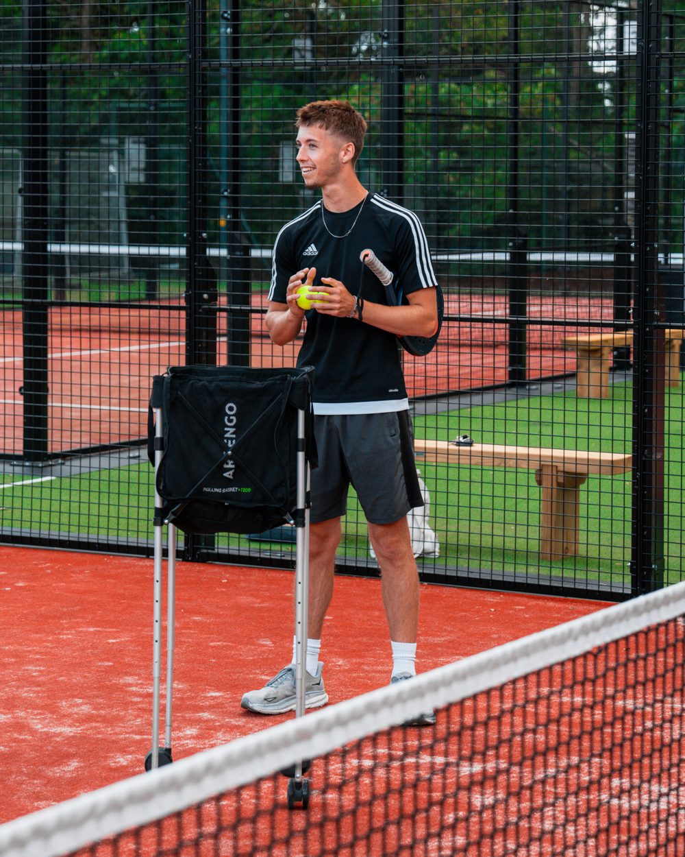 Padel coach at the net on a Ponsbourne court with a ball basket